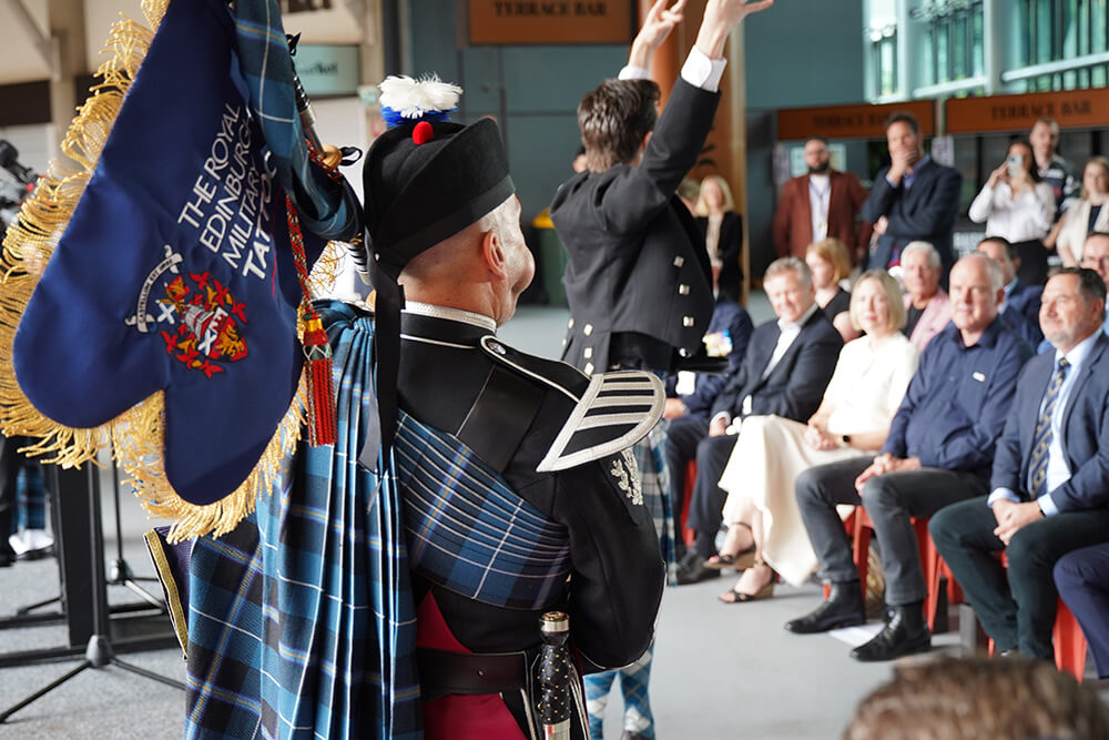 A man dressed in a traditional kilt holds a bagpipe